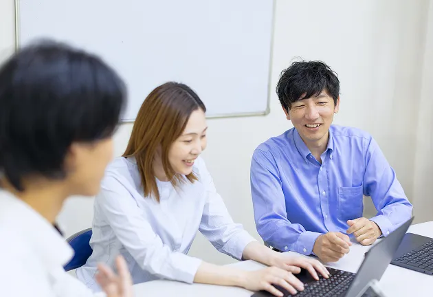 営業職 M.Tさんが他の社員さんと柔らかい雰囲気で会話している様子