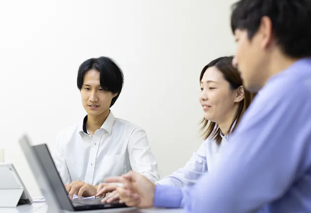 営業職 Y.Aさんが他の社員さんと柔らかい雰囲気で会話している様子